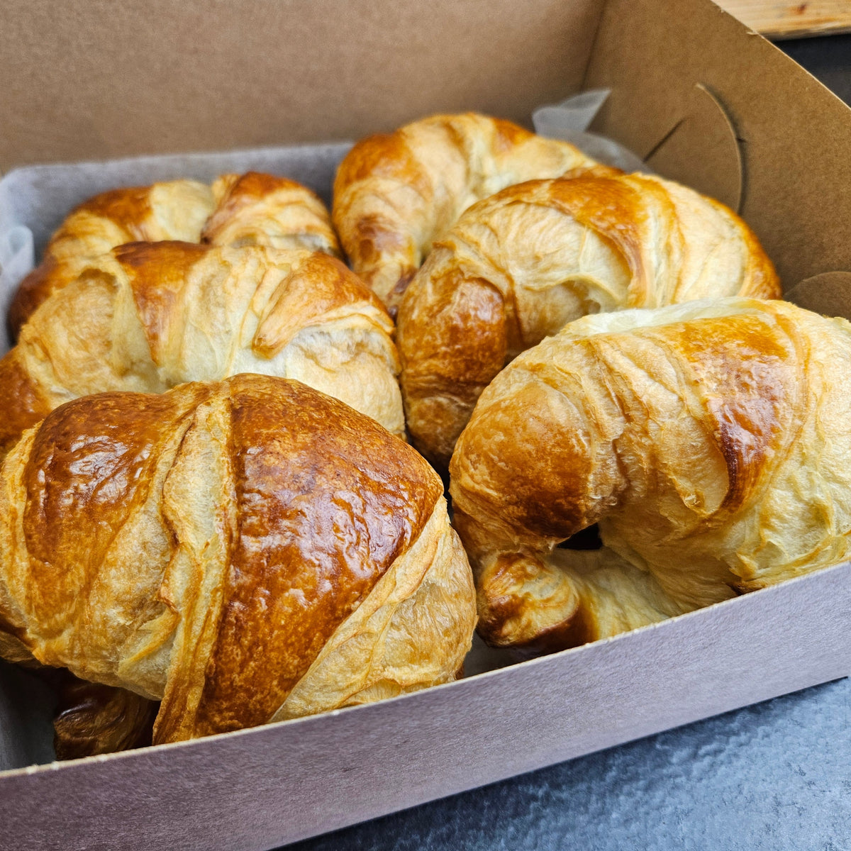 A box of six buttery croissants baked fresh in house, golden and flaky, from the Radical Gardens bakery in Timmins