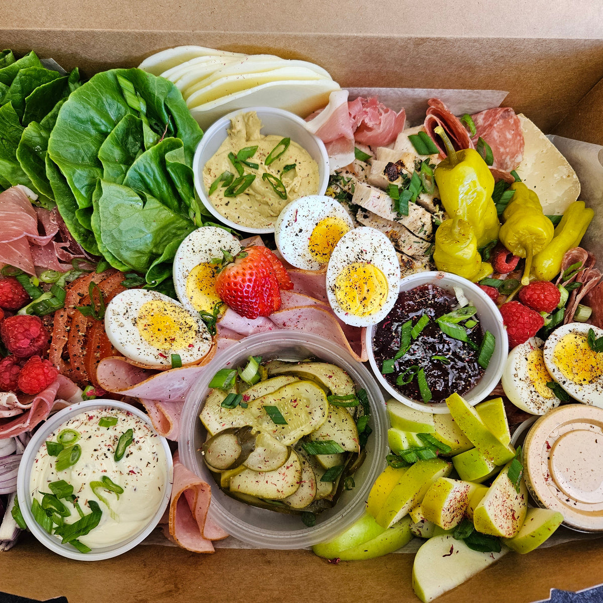 A ploughman's grazing box from Radical Gardens — thick-cut ciabatta, artisan cheese wedges, cold cuts, pickles and chutneys laid out for building sandwiches, Timmins