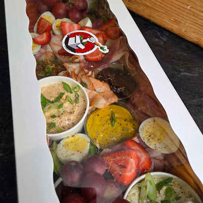 A ploughman's grazing box from Radical Gardens — thick-cut ciabatta, artisan cheese wedges, cold cuts, pickles and chutneys laid out for building sandwiches, Timmins